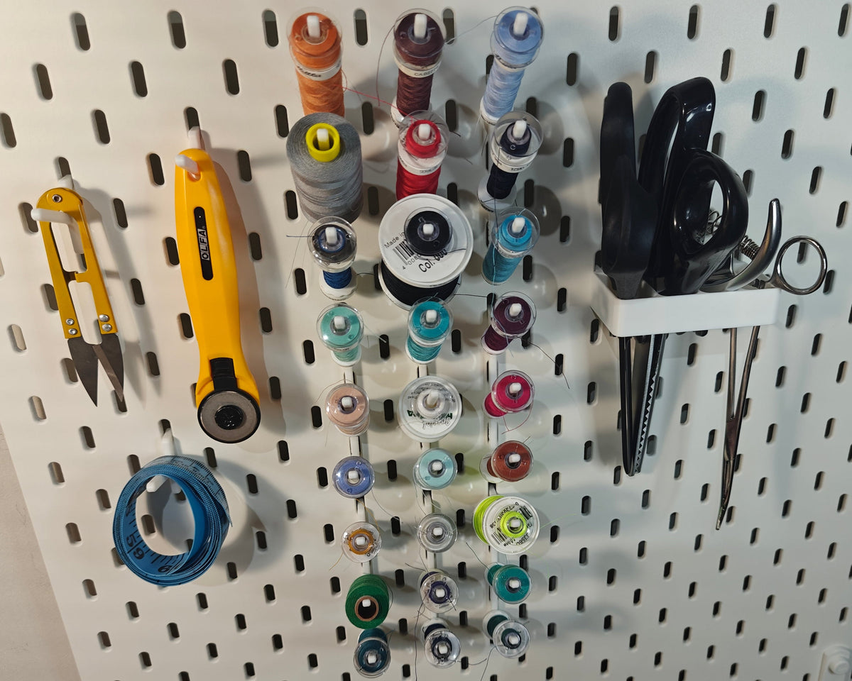 Een foto van het grote naaigaren pakket. Op de foto zie je ge3dprinte artikelen. Een grote haak voor vier scharen, 3 haken voor andere artikelen (zoals een draadknipper, liniaal, meetlint enz) en 9 haken met elk 3 klosjes naaigaren met een spoeltje bij sommige.