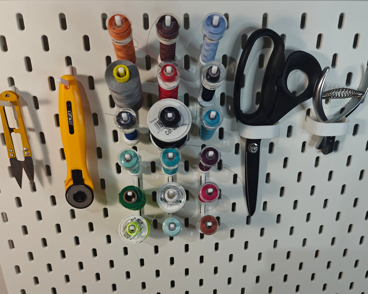 Een foto van het middelgrote naaigaren pakket. Op de foto zie je ge3dprinte artikelen. Twee haken voor een schaar, twee haken voor andere artikelen (zoals een draadknipper, liniaal, meetlint enz) en 6 haken met elk 3 klosjes naaigaren met een spoeltje bij sommige.